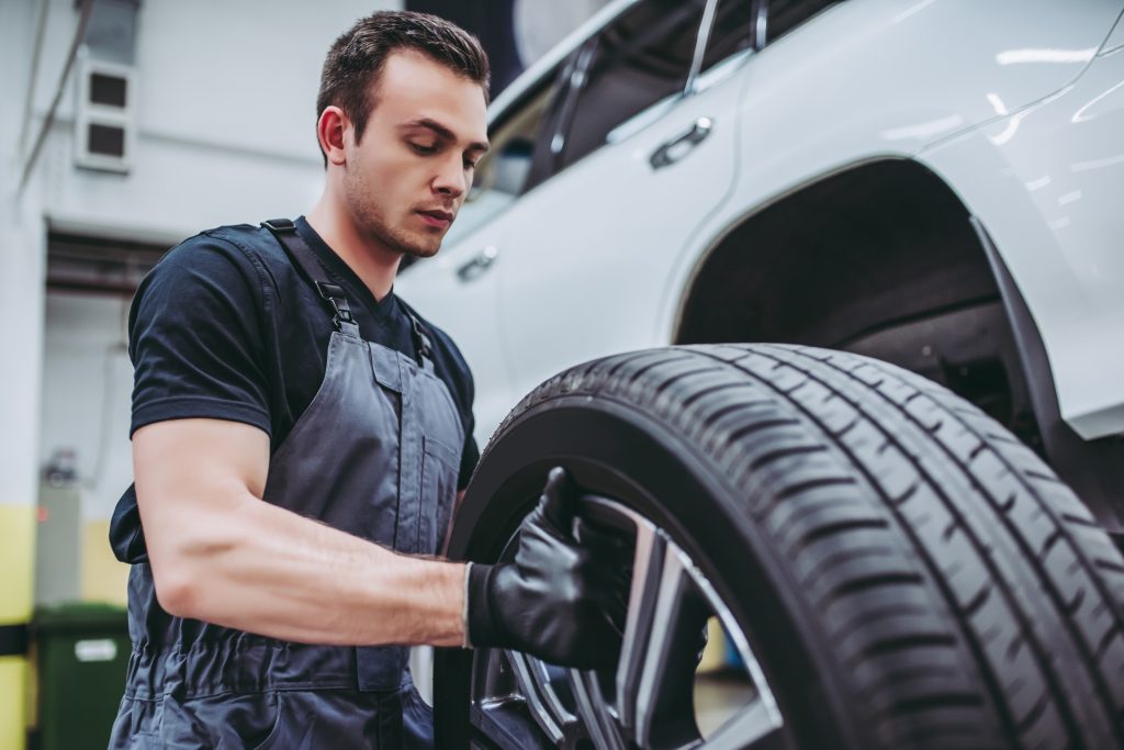 Automotive technician inspecting a vehicle tire during professional tire service.