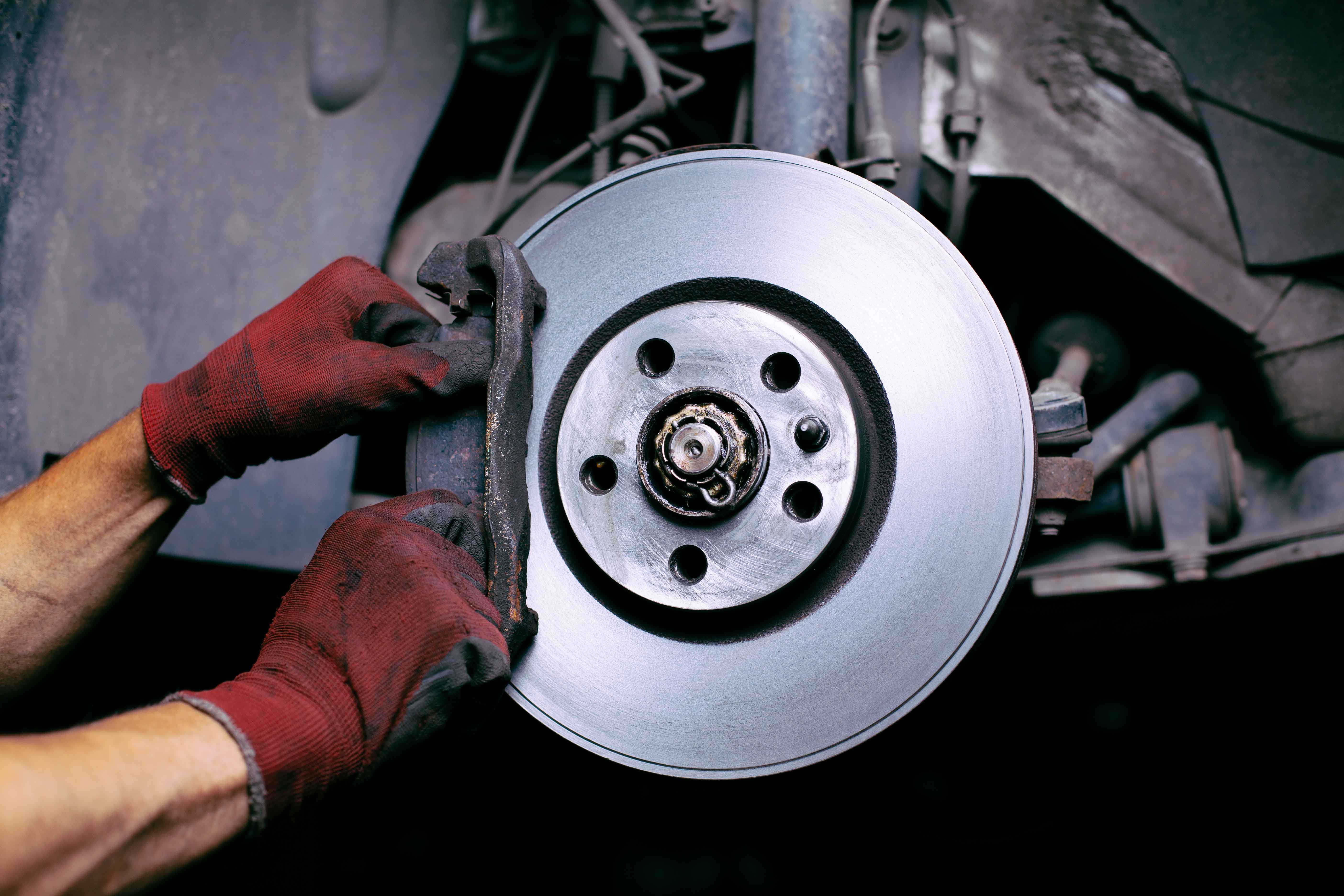 Mechanic inspecting a vehicle brake disc and caliper.