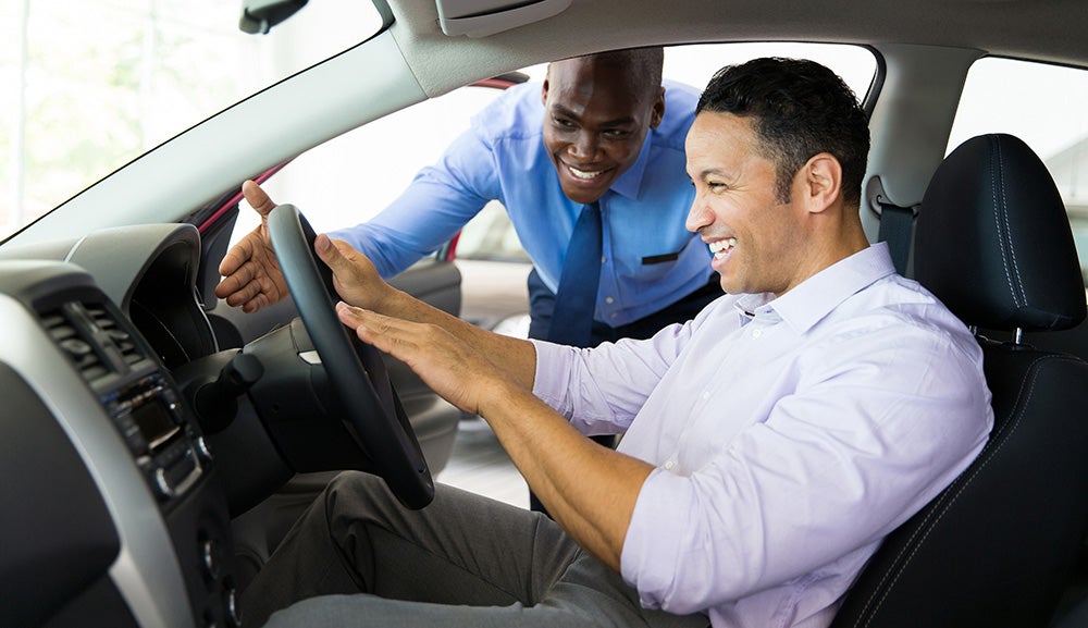 two men smile while inside a car